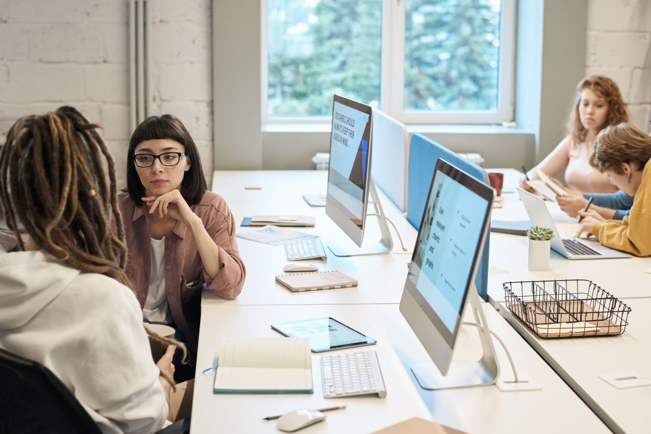 about-01 Diverse group of women working together in a modern office setting, fostering teamwork and creativity.